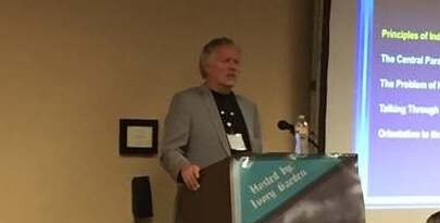 Dr. Colin Ross speaking at the podium at the 2017 Ivory Garden conference